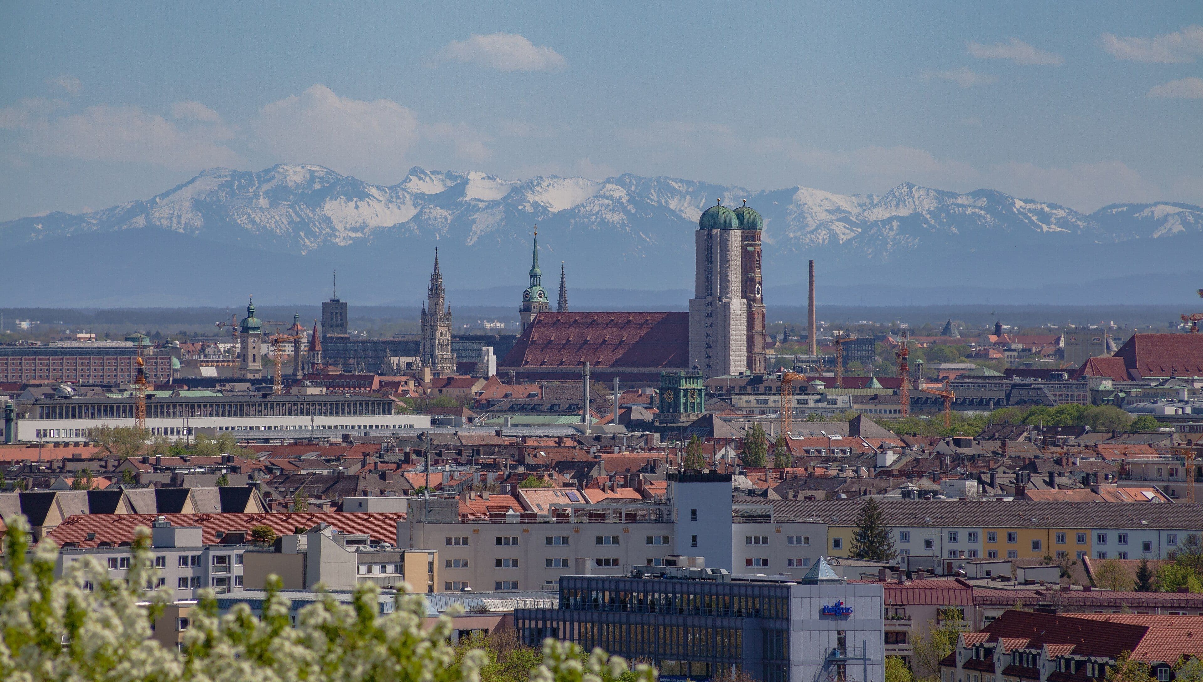 Vista de Múnich desde la Torre Olímpica: las dos cúpulas de la Frauenkirche sobre los tejados y los Alpes nevados al fondo