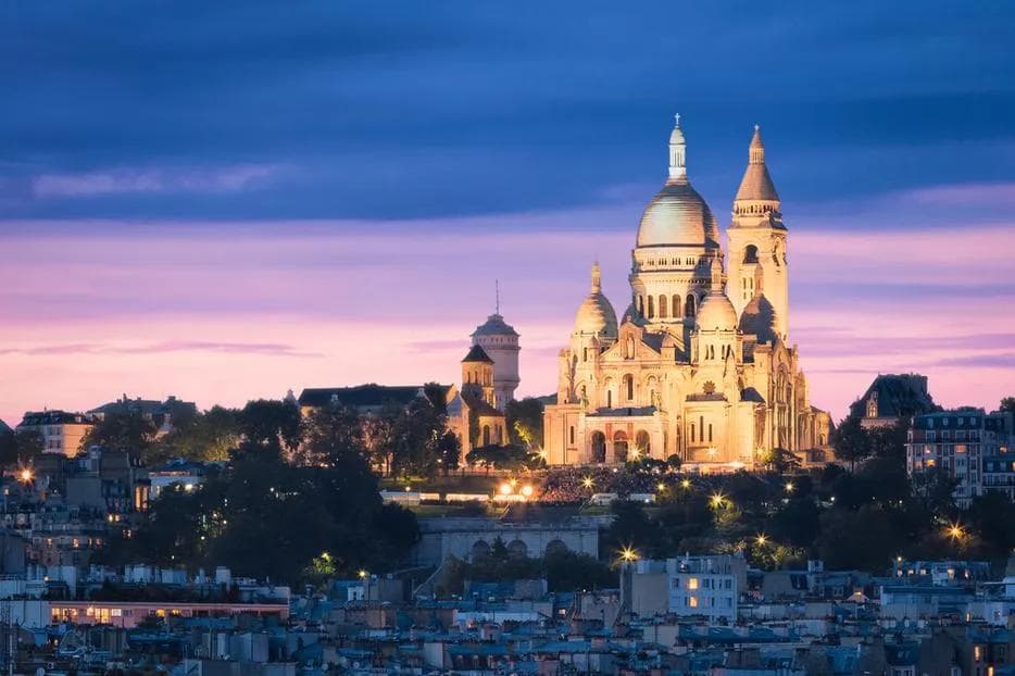 Basílica del Sacré-Cœur iluminada al atardecer sobre los tejados de Montmartre