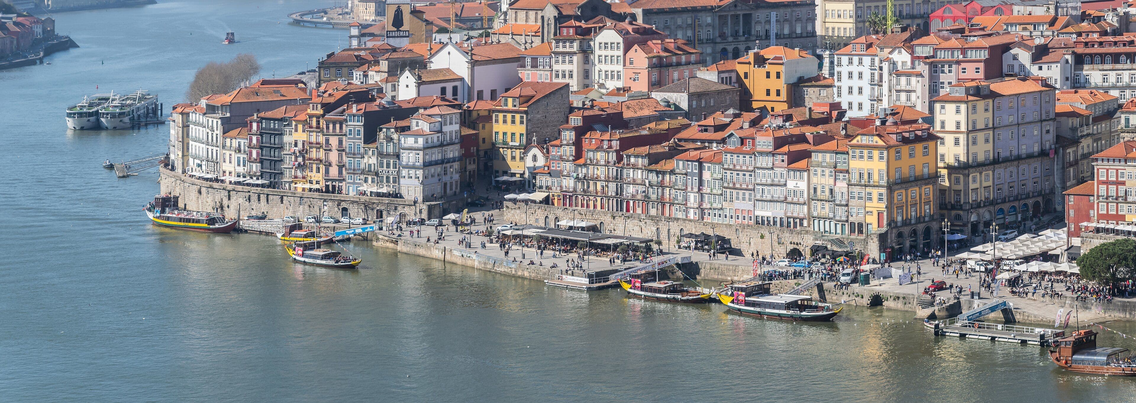 La Ribeira de Oporto vista desde Gaia: las fachadas de colores alineadas sobre el muelle, con el Duero y los barcos rabelos delante