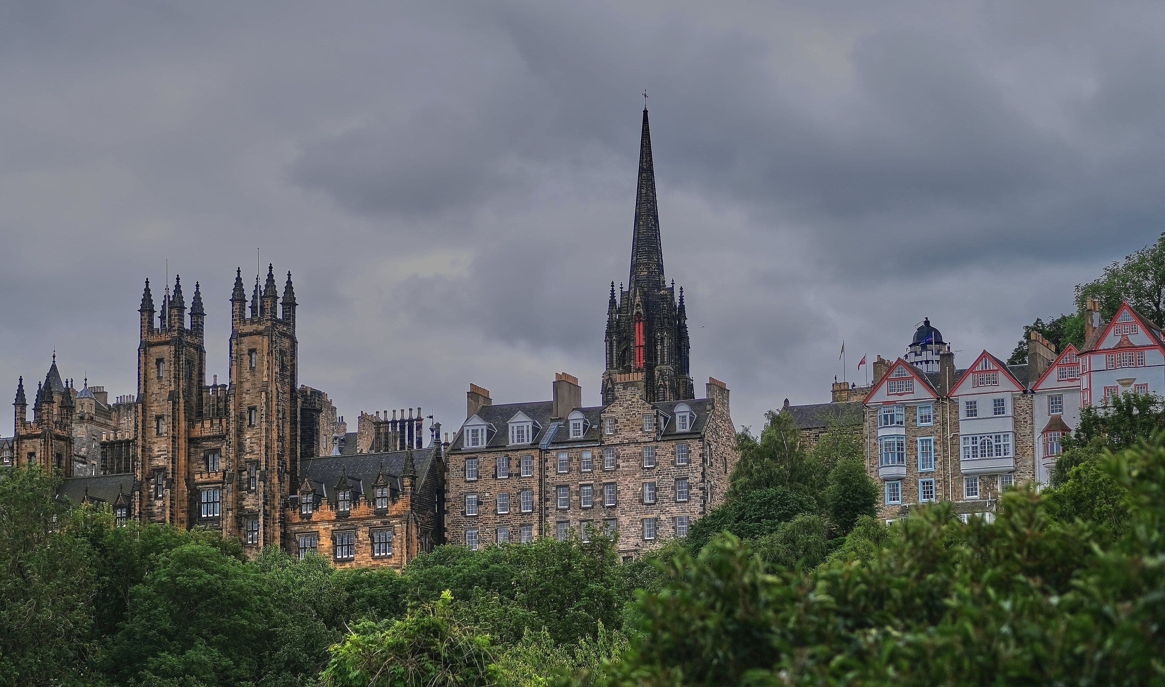 Perfil de la Old Town de Edimburgo con las torres del New College y la aguja del Hub sobre los árboles
