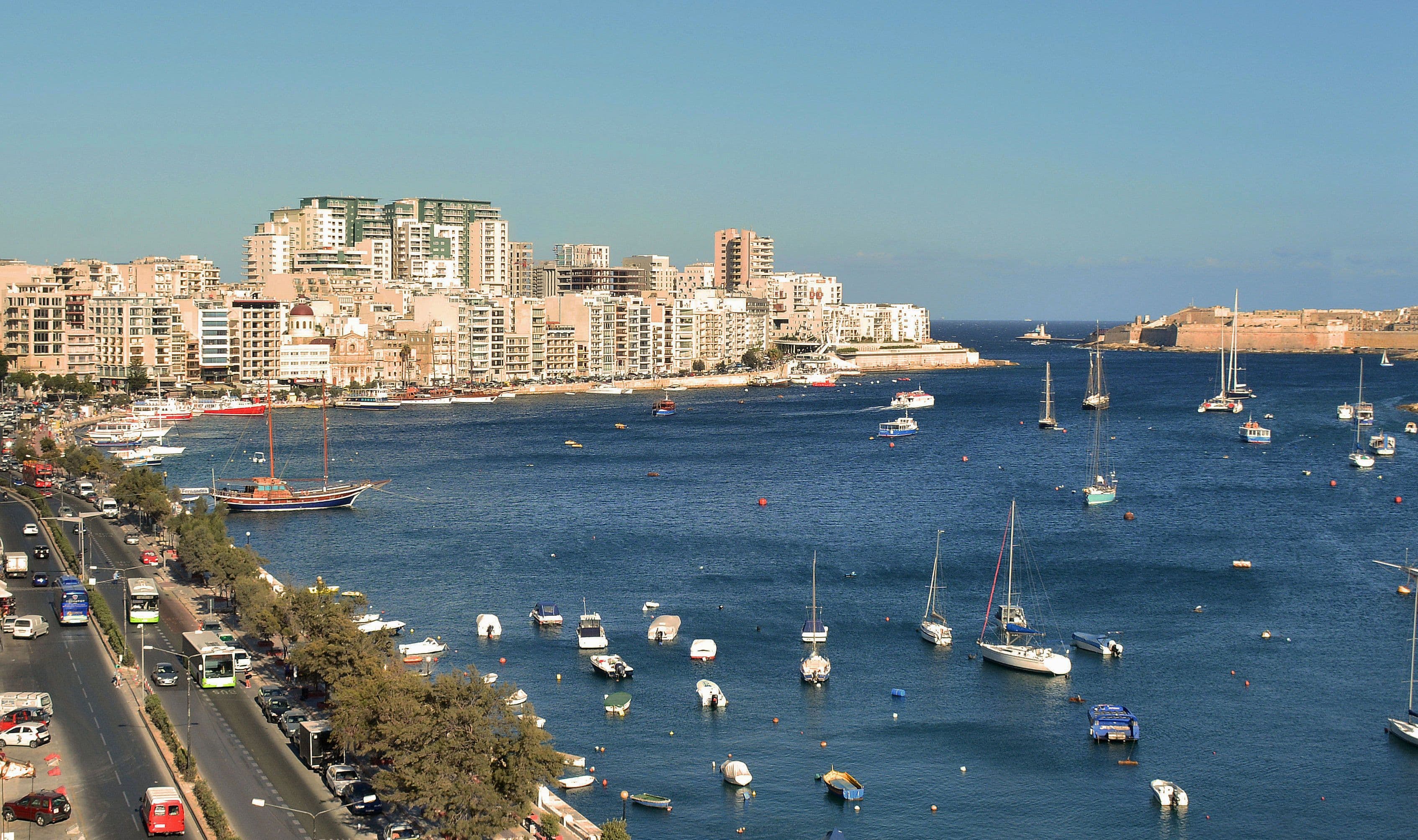 Paseo marítimo de Sliema con la bahía llena de barcas y las fortificaciones de La Valeta al fondo